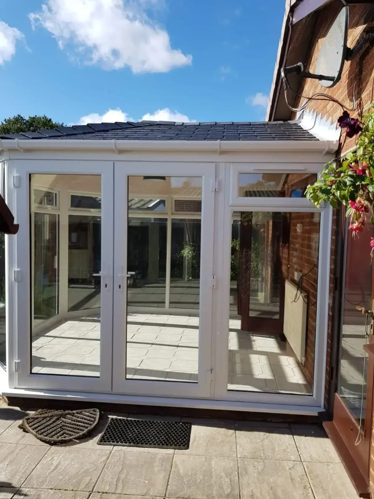 Modern uPVC lean-to conservatory build with elegant French doors opening onto a residential garden patio. Fitted by Norfolk Exterior Solutions